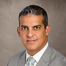 Professional headshot of a man in a suit and tie.